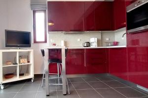 a kitchen with red cabinets and two stools at A balcony of Aegina by the saronic gulf in Egina