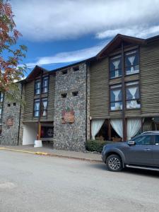 un edificio con un coche aparcado delante de él en Hosteria Posta de los Colonos en Villa La Angostura