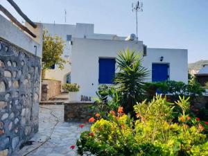 a white house with blue doors and plants at Limni No 3 self catering apartment in Posidhonía