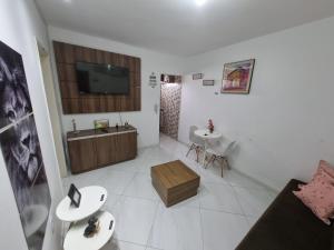 ein Wohnzimmer mit einem TV und 2 Tischen in der Unterkunft Kitnet encantador no centro de campina grande -PB in Campina Grande