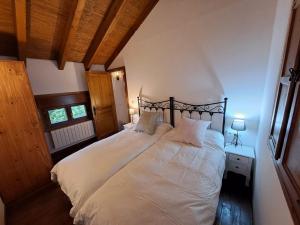 a bedroom with a large bed with white sheets at El Descanso de Sanabria in Trefacio