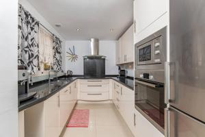 una cocina con armarios blancos y electrodomésticos de acero inoxidable en Fantastic rental with rooftop terrace Aloha Pueblo RDR309, en Marbella