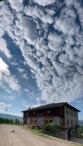 un bâtiment sur le côté d'un chemin de terre avec un ciel nuageux dans l'établissement Agritur Maso Forcola, à Brez