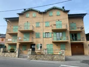 a building with green doors and balconies on it at Chaleureux appartement T4 cosy, Font Romeu Odeillo Via in Font-Romeu-Odeillo-Via