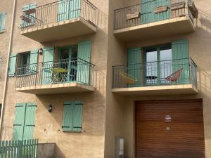 a building with two balconies and a wooden door at Chaleureux appartement T4 cosy, Font Romeu Odeillo Via in Font-Romeu-Odeillo-Via