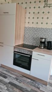 cocina con armarios blancos y fogones en Zimmer, en Nordhausen