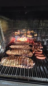 a bunch of meats and sausages on a grill at Pension Parrilla Casa Vicente in Tineo