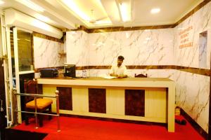 a man sitting at a counter in a room at Aum Karthikeya Residency in Chennai