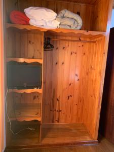 a wooden cabinet with a tv on top of it at Chale para casal c Lareira frigobar microondas Independente in Camanducaia