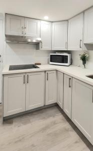 Biała kuchnia z białymi szafkami i kuchenką mikrofalową w obiekcie Deluxe Private Room in North York w mieście Toronto