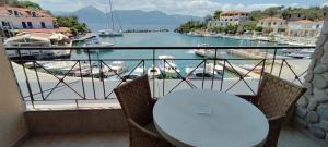 a table on a balcony with a view of a marina at Prego Living Apartments in Vathí