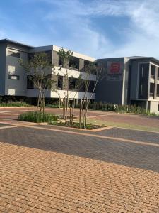 a building with trees in front of a brick road at Zimbali Lakes Boulevard Suites Studio Apartments in Ballito