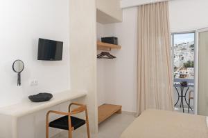 a white bedroom with a desk and a chair at Korali in Astypalaia Town