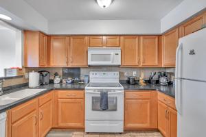 a kitchen with wooden cabinets and a white stove top oven at Cozy Riverfront Condo 25 Min Walk To Broadway And All Nashville Attractions in Nashville