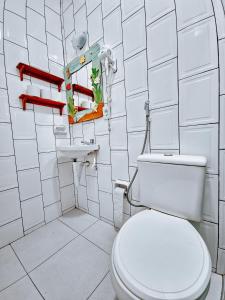 a bathroom with a toilet and a white tiled wall at Suítes Água Marinha in Cabo Frio