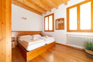 Schlafzimmer mit einem großen Bett, Holzböden und Fenstern in der Unterkunft Locanda 77 in Borso del Grappa