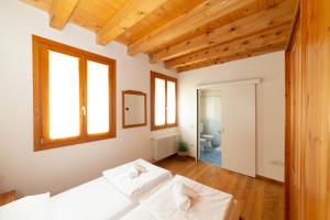 um quarto com 2 camas brancas e tectos em madeira em Locanda 77 em Borso del Grappa