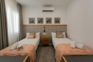 Habitación con 2 camas y sábanas de color naranja y blanco. en Lujoso apartamento con piscina compartida 2 en Sevilla