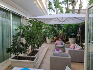 a patio with chairs and an umbrella and plants at Falli Exclusive Rooms and Breakfast in Porto Cesareo