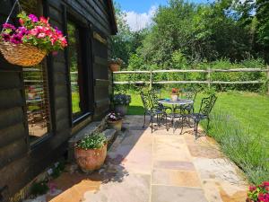 un patio con mesa, sillas y flores en Gatwick hideout, en Charlwood