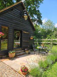 a black cabin with a patio and a table and chairs at Gatwick hideout in Charlwood