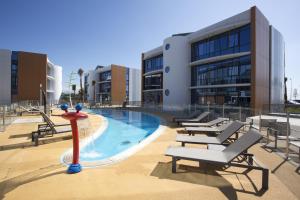 une piscine avec des chaises longues et un bâtiment dans l'établissement Marineland Hôtel, à Antibes