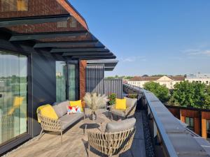 d'une terrasse avec des chaises et un canapé sur un balcon. dans l'établissement Artisa Riia Str 20a Luxury 2BR Penthouse Apartment, à Tartu