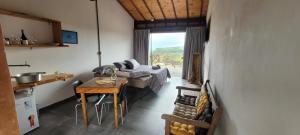 a living room with a bed and a table in a room at Hospedagem Pé de Serra in Botucatu