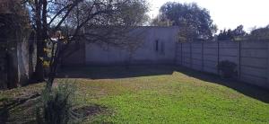 un patio trasero con una valla blanca y un patio de césped en Lo de la Nercida en Tornquist