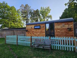 a tiny house with a fence and two chairs at Gatwick Hideaway Hut in Charlwood