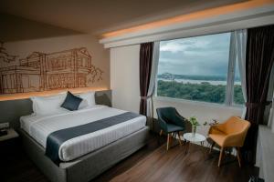 ヤンゴンにあるThe Rangoon Hotelのベッドと大きな窓が備わるホテルルームです。