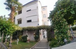 a white house with a palm tree and plants at Apartments Sliško in Poreč