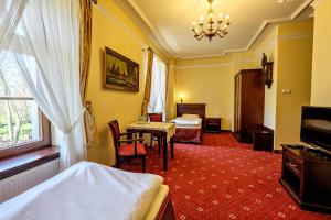 a hotel room with a bedroom with a bed and a table at Dwór Stary Chotów in Kalisz