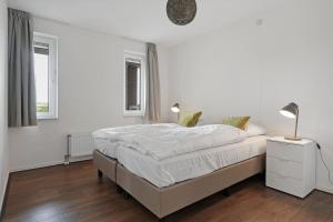 a white bedroom with a bed and two windows at Appartement Ibiza in Zeeland Kabbelaarsbank 411 Port Marina Zélande Ouddorp - not for companies in Ouddorp