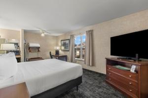 a hotel room with a bed and a flat screen tv at Beach House Inn in Fort Bragg