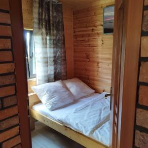 a bed in a wooden cabin with a door open at Domki Letniskowe Meduza in Jarosławiec