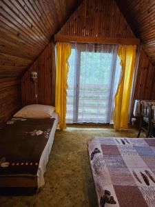 a bedroom with two beds and a window with yellow curtains at Chata Dajana in Stará Lesná
