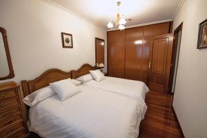 sypialnia z łóżkiem z białymi prześcieradłami i drewnianą podłogą w obiekcie APARTAMENTO AVELINA w mieście Monforte de Lemos