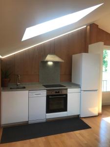 a kitchen with white appliances and wooden cabinets at Tajonar Ático Jardín in Tajonar