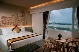 um quarto de hotel com uma cama e uma janela grande em The Rangoon Hotel em Yangon