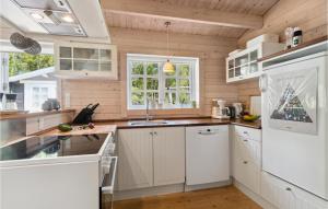 - une cuisine avec des appareils blancs et des murs en bois dans l'établissement Amazing Home In Hadsund With Kitchen, à Hadsund