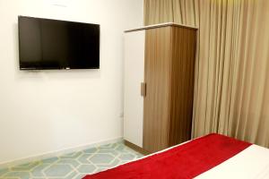 a bedroom with a flat screen tv and a bed at Alezz Suites Salalah in Salalah