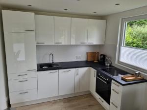 a kitchen with white cabinets and a sink and a window at Ferienhaus Diemelaue in Bad Karlshafen