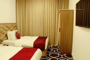 a hotel room with two beds and a television at Alezz Suites Salalah in Salalah