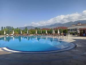 a large swimming pool with chairs and umbrellas at Иссык-Куль,Частный таунхаус-всего минута до пляжа в ЦО "Karven Four Seasons" Issyk-Kul in Chon-Sary-Oy