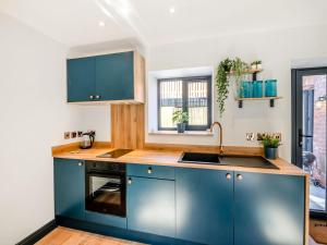 una cocina con armarios azules y fregadero en The Hive - Uk42857 en Rise