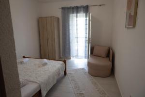 um pequeno quarto com uma cama e uma cadeira em Apartman Delać em Tivat