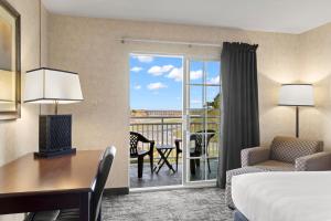 a hotel room with a bed and a desk and a balcony at Beach House Inn in Fort Bragg