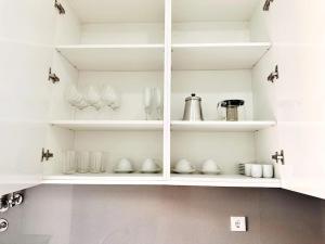 a white cabinet filled with glasses and vases at Lucky Alameda Apartment in Lisbon
