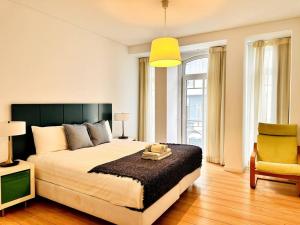 um quarto com uma cama grande e uma cadeira amarela em Lucky Alameda Apartment em Lisboa